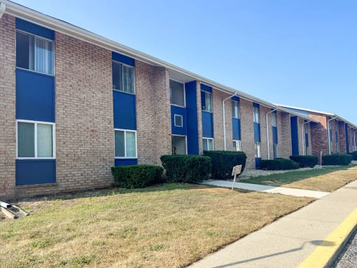 a brick building with blue windows and a sidewalk