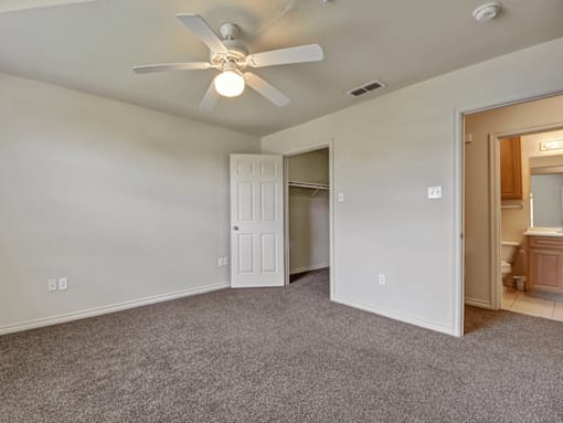 A room with a ceiling fan and carpeted floor.