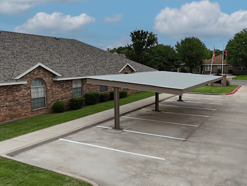 A parking lot in front of a brick building with a metal roof.