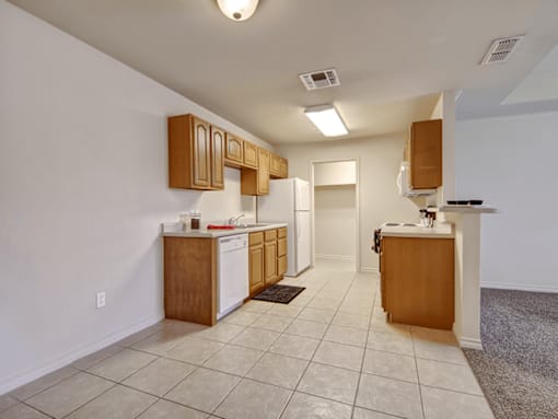 A kitchen with white walls and brown cabinets.