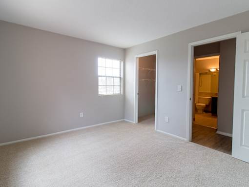 A room with a carpeted floor and a window.