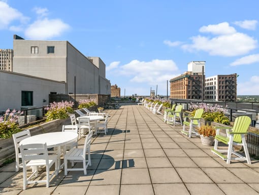 a roof terrace with tables and chairs and buildings in the background