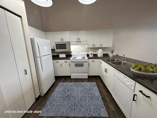 A kitchen with white cabinets and a blue rug on the floor.