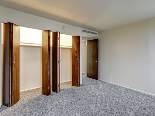 A room with a carpeted floor and four wooden doors.