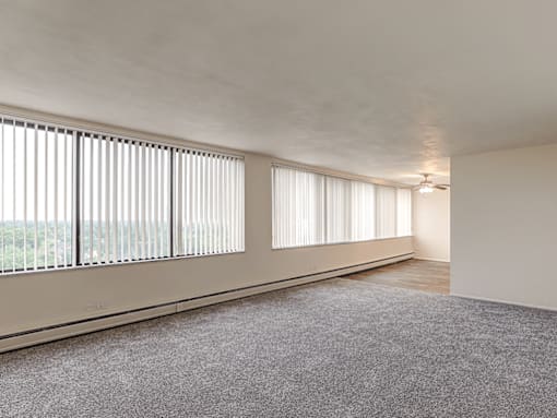 A room with a carpeted floor and a window with blinds.