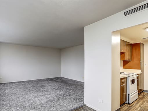 A kitchen area is visible through an open door in a white room.