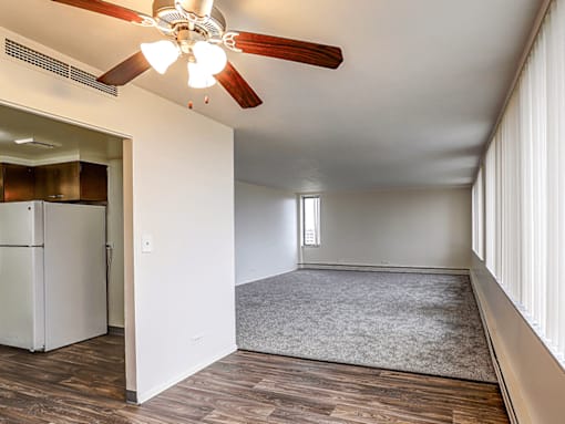 A room with a ceiling fan and a refrigerator.