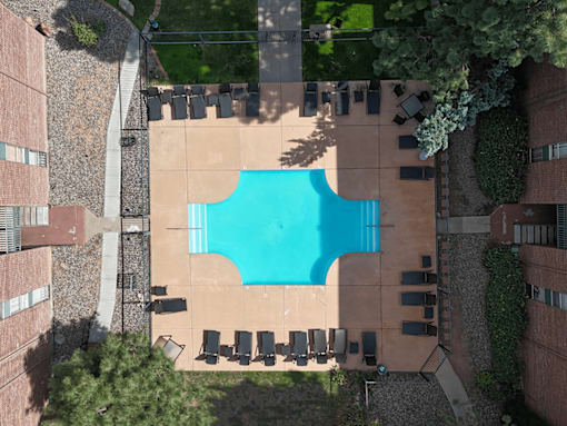An aerial view of a pool surrounded by chairs and buildings.