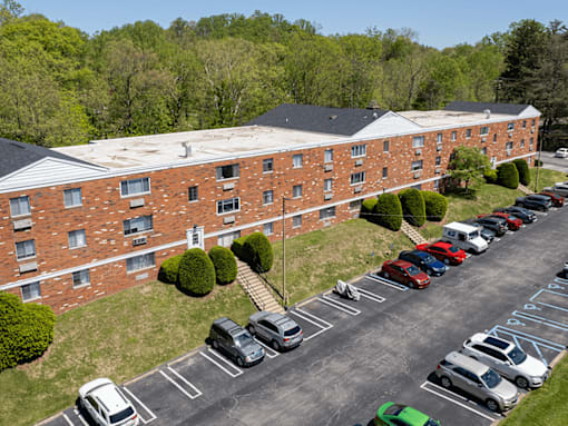 A parking lot with cars parked in front of a red brick building.