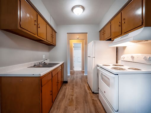 A kitchen with white appliances and wooden cabinets.