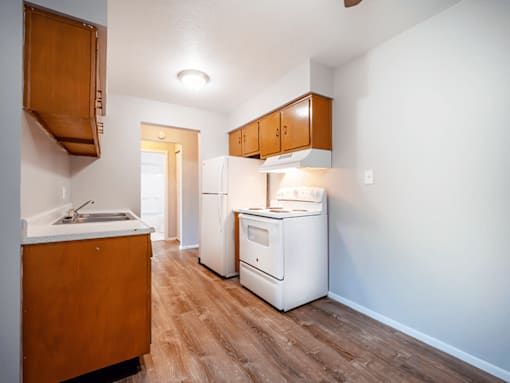 A kitchen with a white fridge and wooden cabinets.