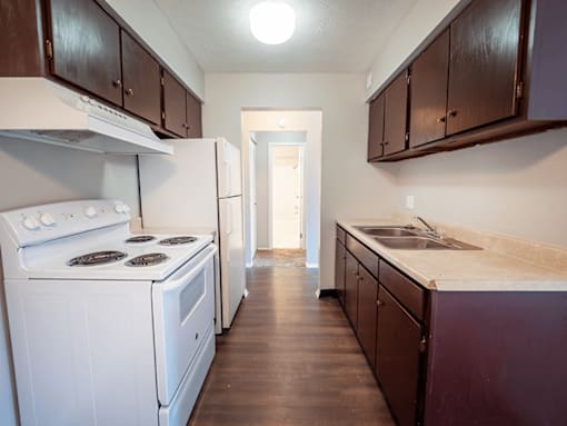 A kitchen with white appliances and dark wood cabinets.