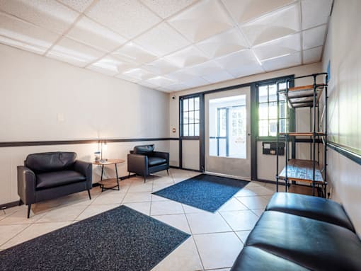 A waiting room with black leather chairs and a white ceiling.