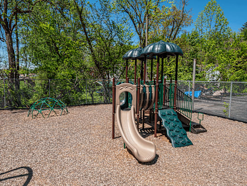 A playground with a brown slide and a green canopy.