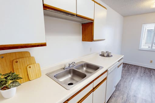A kitchen with a white counter top and a wooden cabinet.