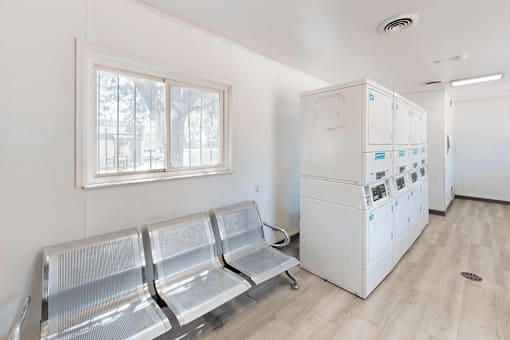 A waiting room with a row of chairs and a white cabinet with drawers.