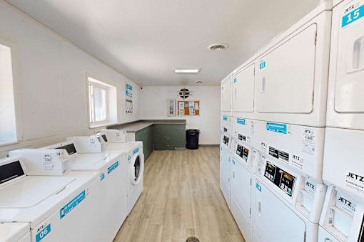 A row of white washing machines are lined up in a laundry room.