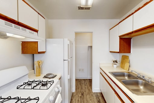 A kitchen with a white gas stove and white cabinets.
