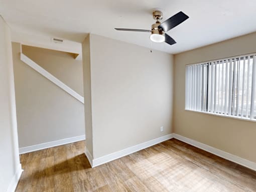 A room with a ceiling fan and a window with blinds.