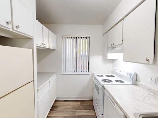 A small kitchen with white appliances and wooden floors.