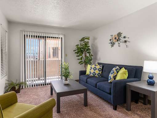 A living room with a blue couch, a yellow chair, and a wooden coffee table.