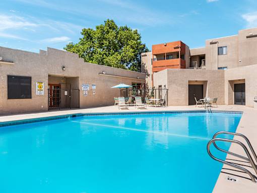 A swimming pool in front of a building with a blue sky in the background.