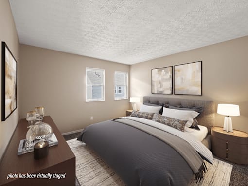 A bedroom with a large bed and a nightstand with a lamp.