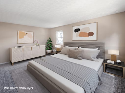 A bedroom with a large bed and a nightstand with a lamp.