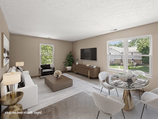 A living room with a white couch, a coffee table, a TV, and a dining table.