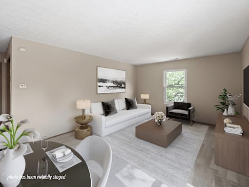 A modern living room with a white sofa, a coffee table, and a large window.