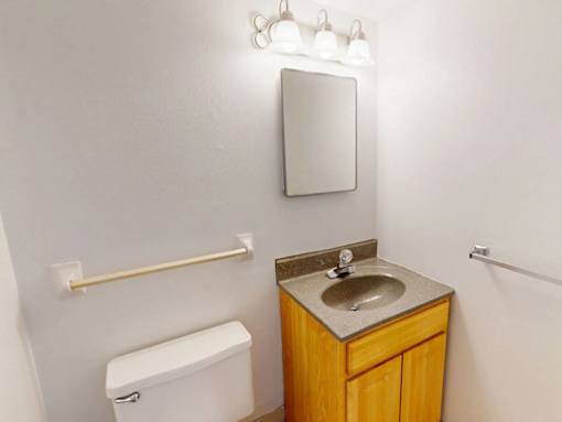 A bathroom with a toilet, sink and mirror.