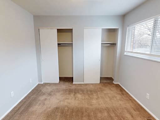 A room with carpeted floor and two closets.