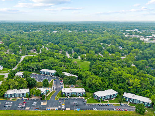 aerial view of an apartment complex with parking lot and trees