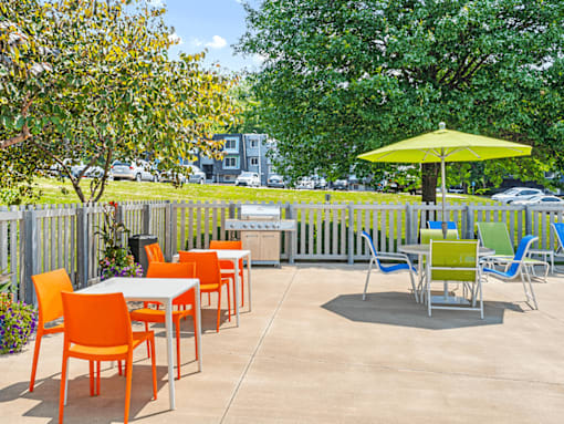 a patio with tables and chairs and a yellow umbrella