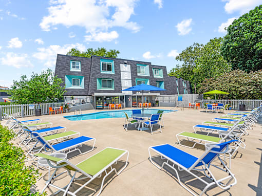 a pool with chairs and umbrellas in front of a building