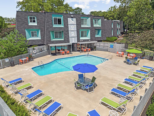 an aerial view of a swimming pool and patio with chairs and an umbrella