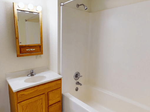 A white sink with a wooden cabinet and a mirror above it.