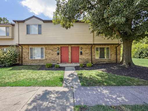 A house with a red door and a tree in front.
