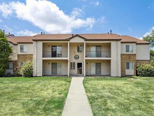 A large apartment building with a green lawn in front.