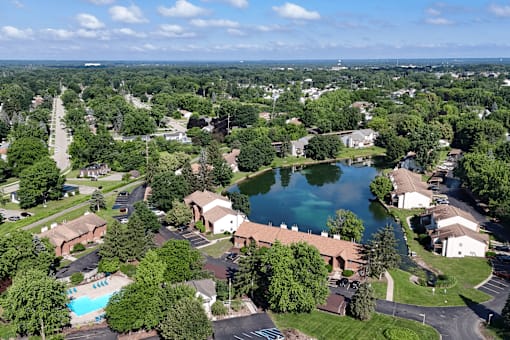 A bird's eye view of a residential area with a swimming pool and a lake.