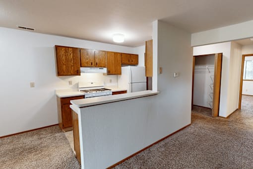 A kitchen with white walls and wooden cabinets.