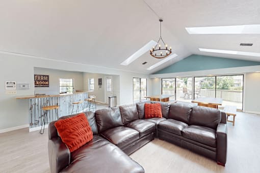 A living room with a large couch and a bar area in the background.