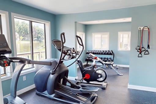 A gym with a treadmill, exercise bike, and weights.