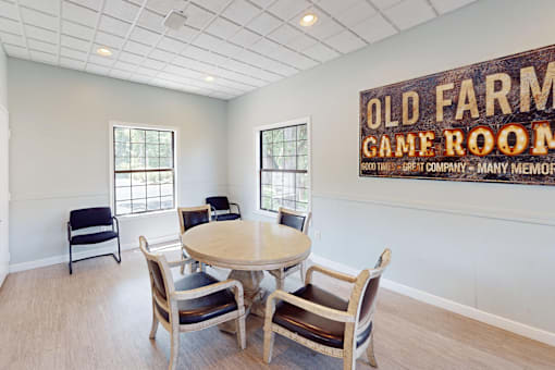 A room with a table and chairs and a sign that says Old Farm Game Room.
