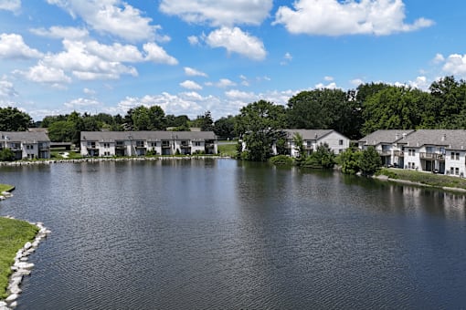 A lake surrounded by houses and trees under a blue sky.