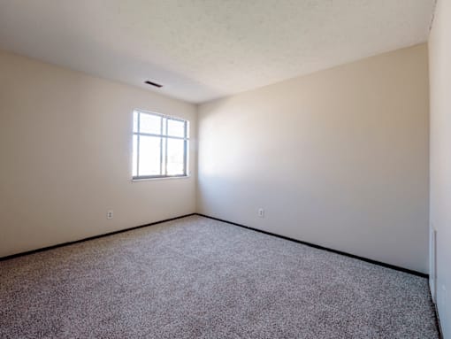A room with a window and carpeted floor.