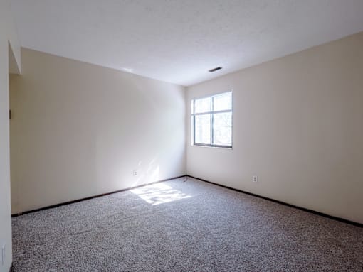 A room with a window and carpeted floor.