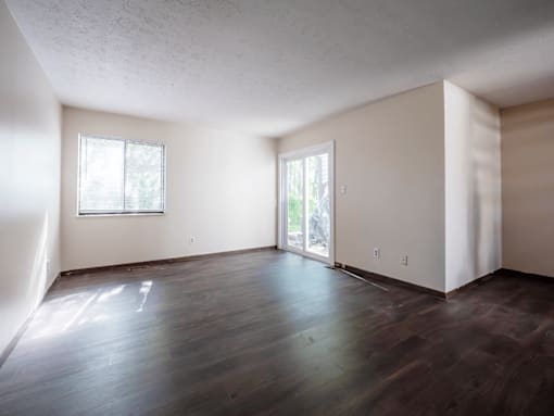 A room with wooden floors and two windows.