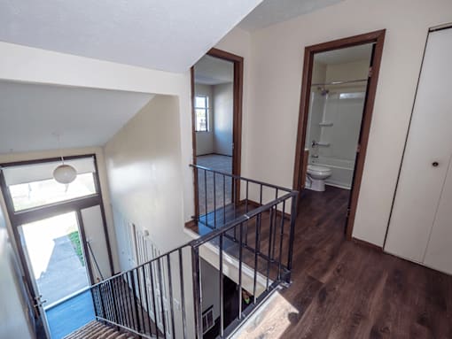 A staircase with a metal railing leads to a bathroom.