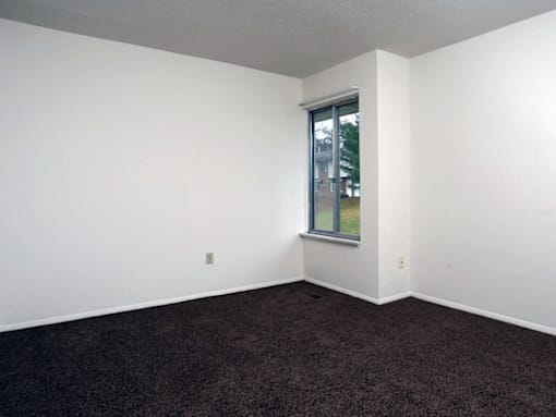 A room with a window and carpeted floor.